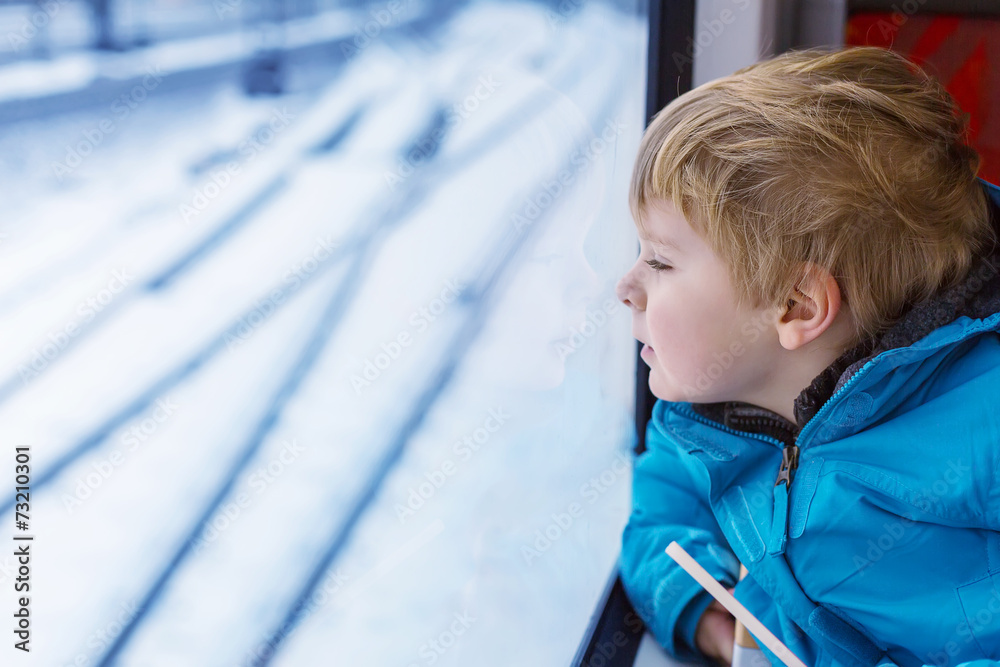 Adorable little kid traveling and looking out train window outsi