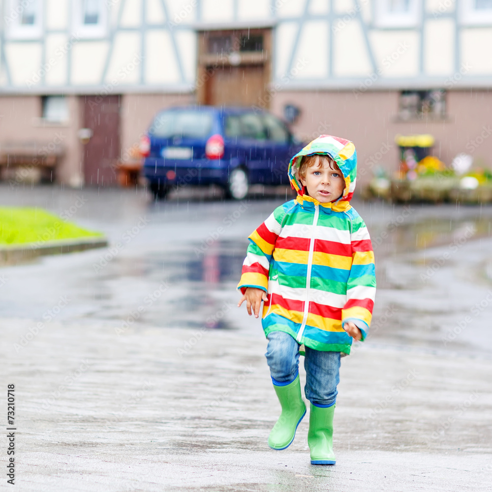 Happy smiling little boy walking in city through rain Happy smiling little boy walking in city through rain