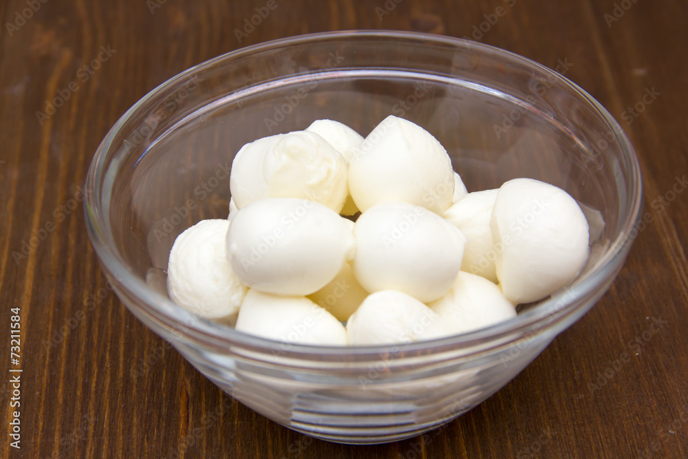 Small mozzarella in bowl on wooden table Small mozzarella in bowl on wooden table