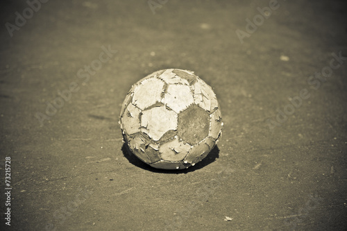 old soccer ball outdoors. photo toned yellow