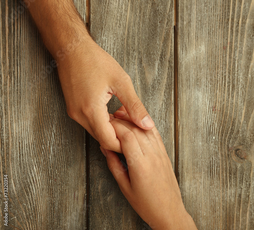 Loving couple holding hands close-up on wooden background