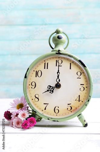 Fototapeta Naklejka Na Ścianę i Meble -  Beautiful flowers with clock on table on light blue background