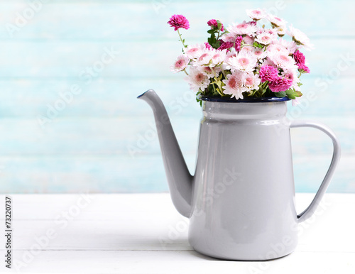 Fototapeta Naklejka Na Ścianę i Meble -  Beautiful flowers in pitcher on table on light blue background