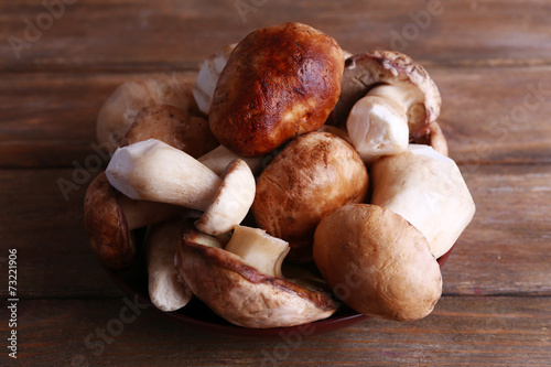 Wild mushrooms on plate on wooden background