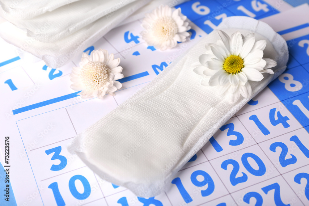 Sanitary pads and white flowers on blue calendar background Sanitary pads and white flowers on blue calendar background