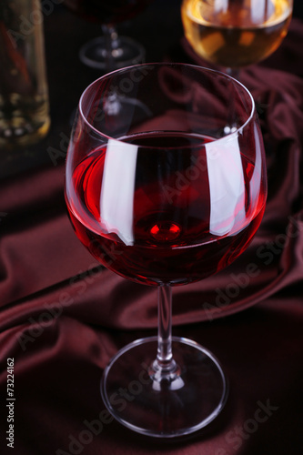 Red wine glass with bottles and glasses of wine close-up