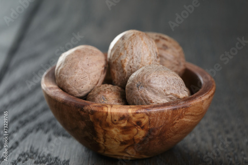 whole nutmegs in olive bowl on oak table