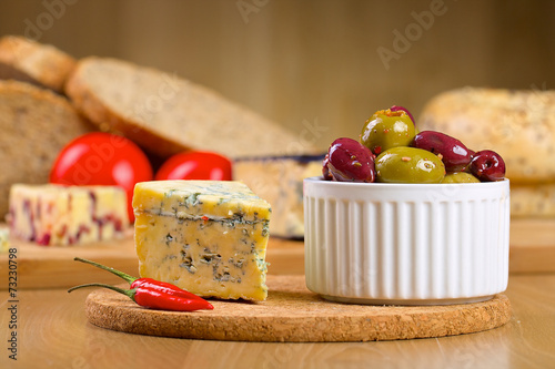 Blue cheese and olives on a wooden serving board
