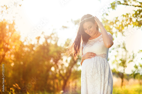 Pregnant woman in white dress in nature