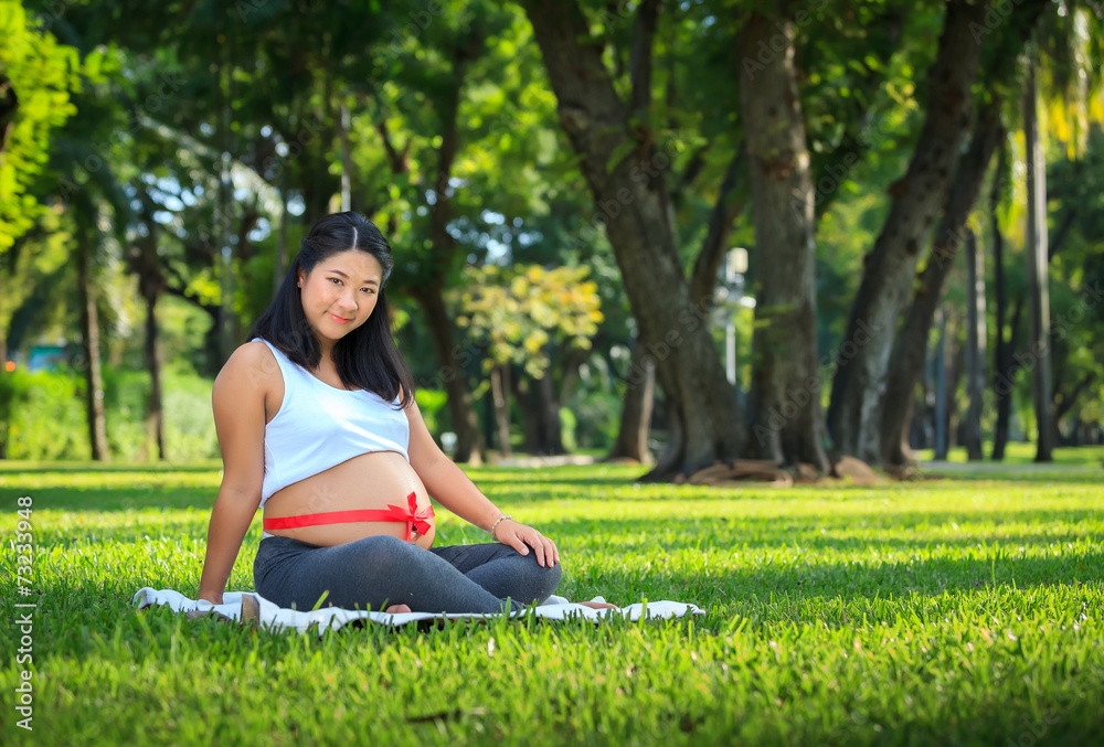 Beautiful pregnant asian woman relaxing in the park with red rib