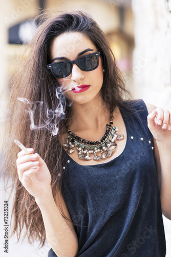 Glamorous brunette woman with sunglasses smoking.
