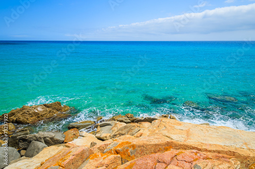 Rocks in turquoise sea on coast of Sardinia island at Rei