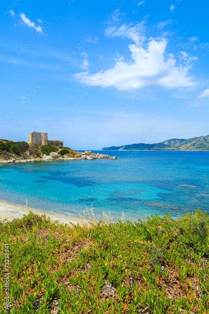 Beach with azure sea and castle on coast of Sardinia island