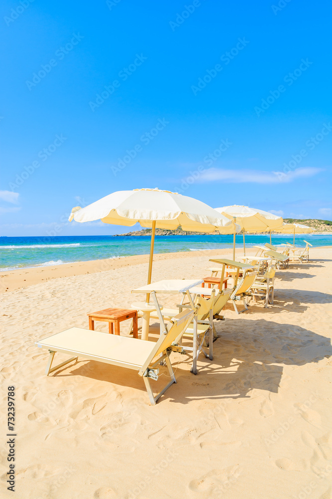 Sunbeds with umbrellas on Sa Colonia beach, Sardinia island