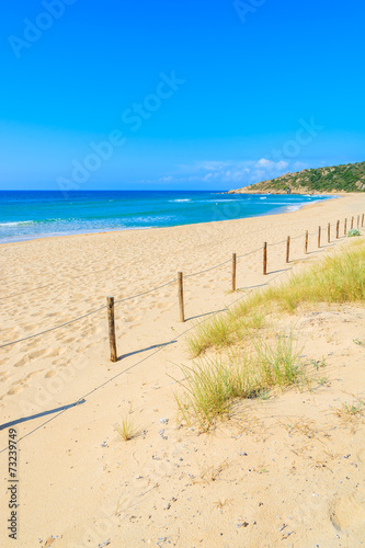 Fototapeta Naklejka Na Ścianę i Meble -  Wooden fence and grass on sand dune, Chia beach, Sardinia island