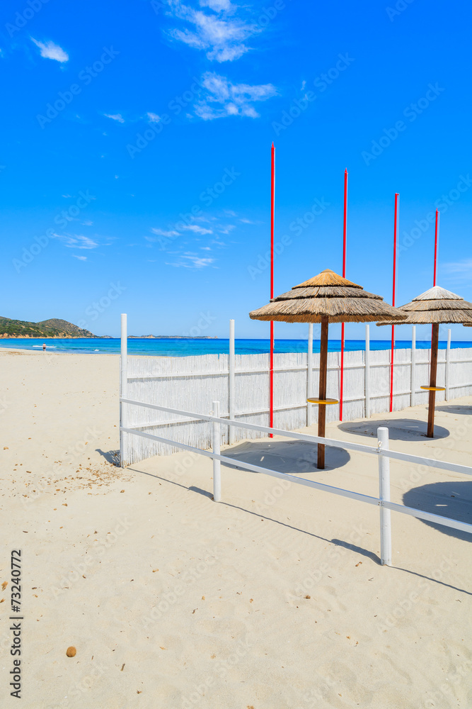 Fototapeta premium Sunbeds with umbrellas on Villasimius sandy beach, Sardinia