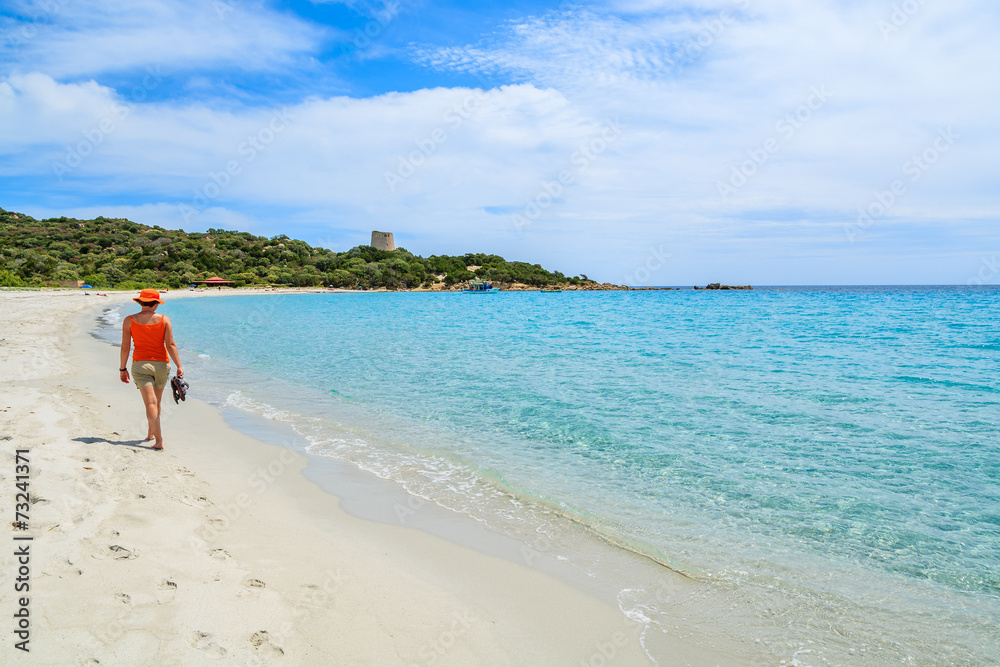 Young woman walking on white sand beach, Cala Pira, Sardinia Young woman walking on white sand beach, Cala Pira, Sardinia
