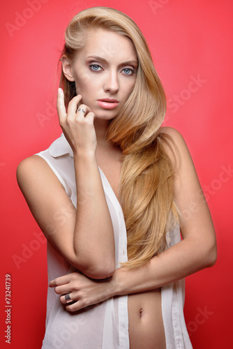 Beautiful seminude blonde woman at red background.