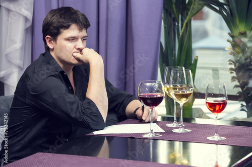 young man tasting wine at a table in a restaurant