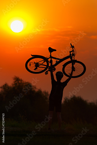 Tourist with a bike on the sunset background.