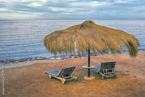 Two beach chairs with sun umbrella on beautiful beach.