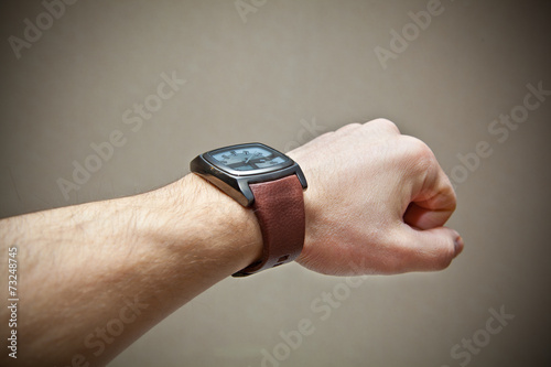 Brutal man's hand with a wrist watch on a gray background