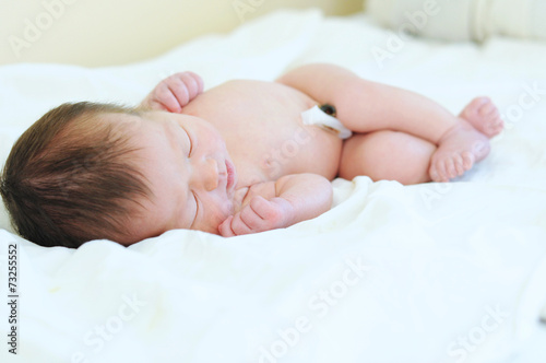Newborn baby with umbilical cord sleeping undressed