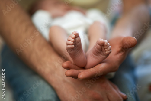 Dad holds in his hands small baby foot