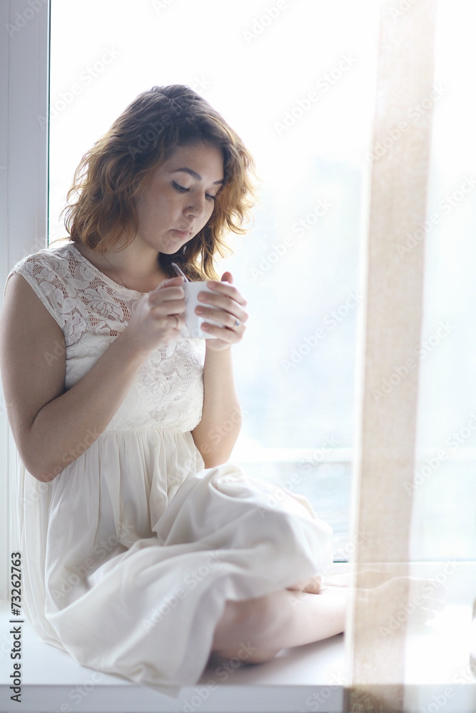 Pregnant girl sitting on the windowsill Pregnant girl sitting on the windowsill