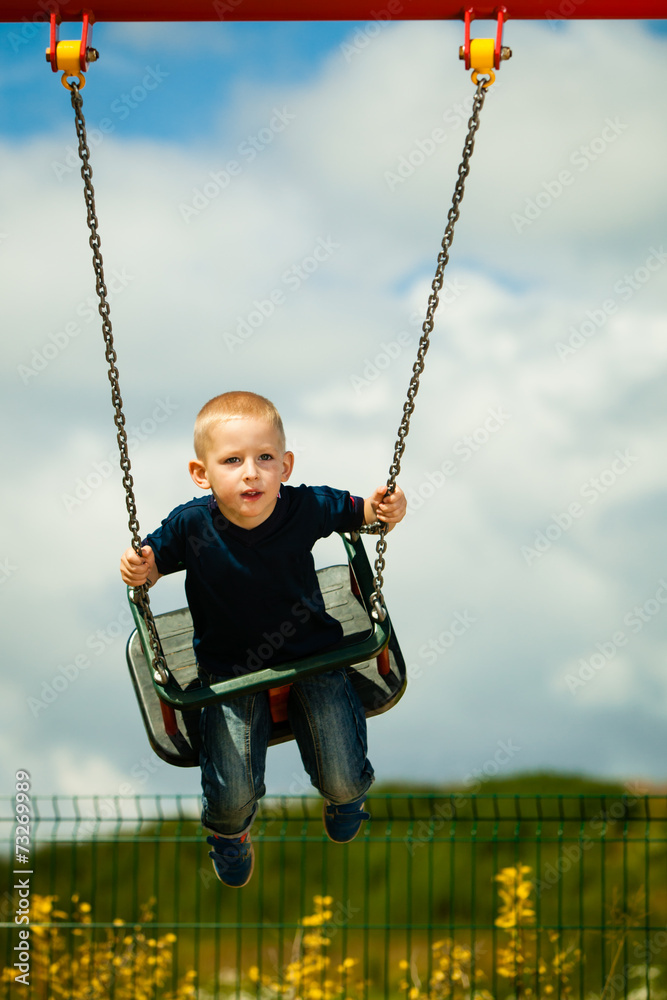 Little boy having fun at the playground on swing