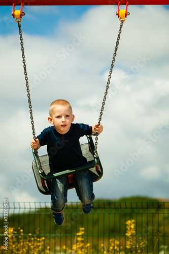 Little boy having fun at the playground on swing