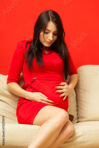 pregnant woman relaxing on sofa touching her belly