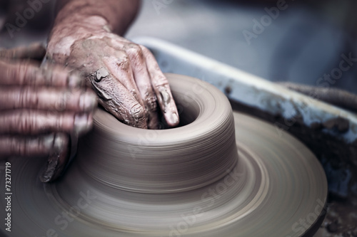 Hands working on pottery wheel ,  artistic  toned