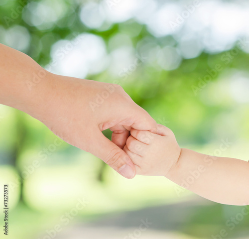 Baby hand holding her mother finger in garden © gamelover