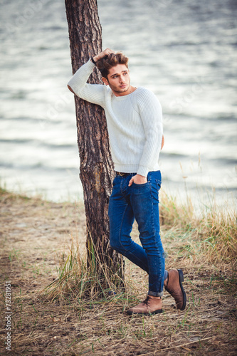 young man on sea background. autumn beach