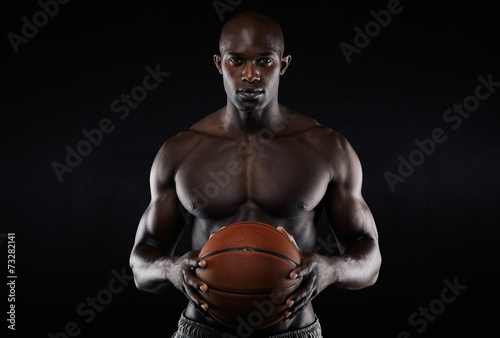 Muscular young man shirtless holding a basketball