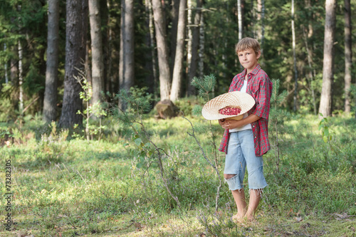 Teenage boy holding hat full of red wildberries photo