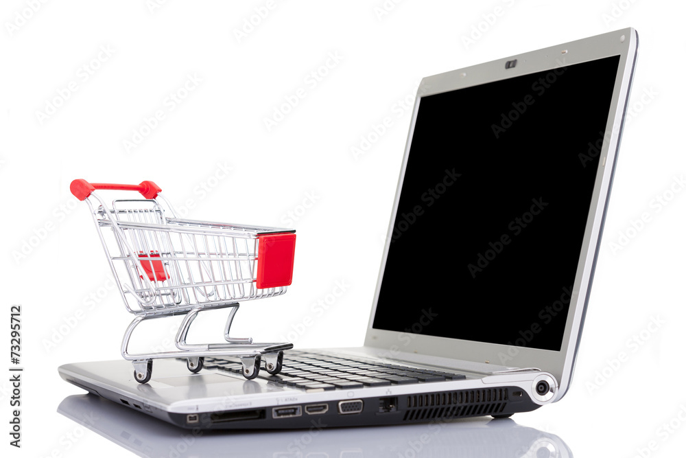 Shopping cart over a laptop computer, isolated on white backgrou