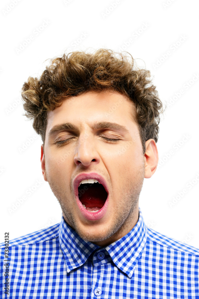 Portrait of a young man yawning over white background Portrait of a young man yawning over white background