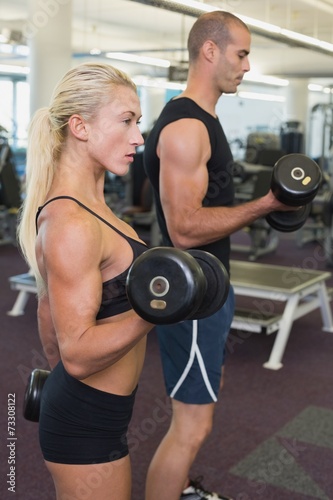 Couple exercising with dumbbells in gym