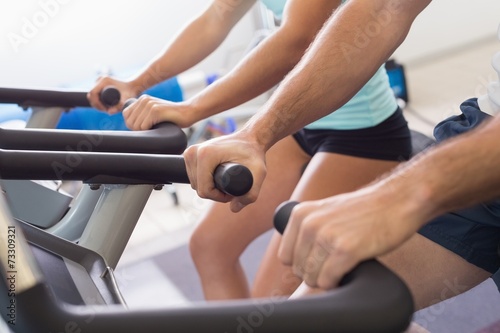 Mid section of couple working on exercise bikes at gym