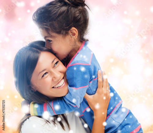 smiling little girl and mother hugging indoors