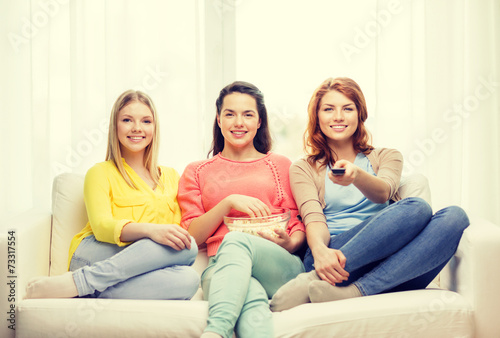 three smiling teenage girl watching tv at home