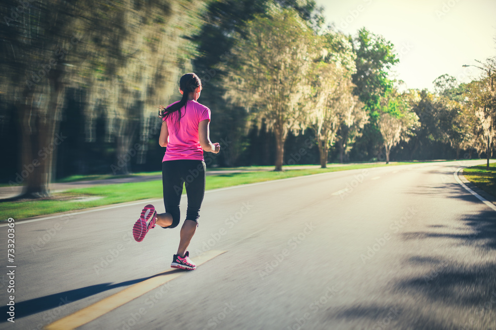 Fototapeta premium Young woman running outdoors at sunrise or sunset.