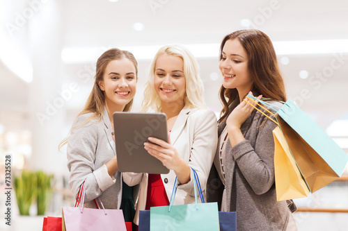 happy young women with tablet pc and shopping bags