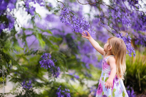 Photography happy little girl has a fun in blossom jacaranda garden