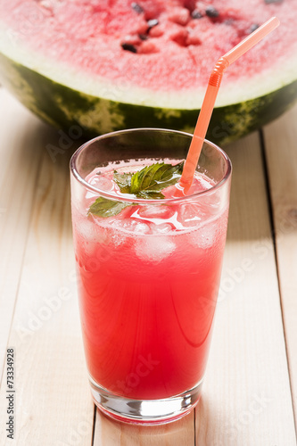 Glass of fresh watermelon juice with mint leaves and ice, on woo