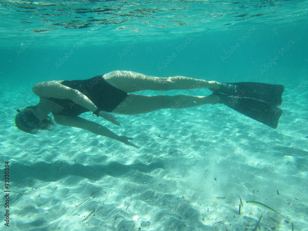 Female swimmer diving underwater in ocean