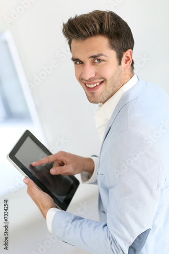 Attractive smiling man with jacket using digital tablet