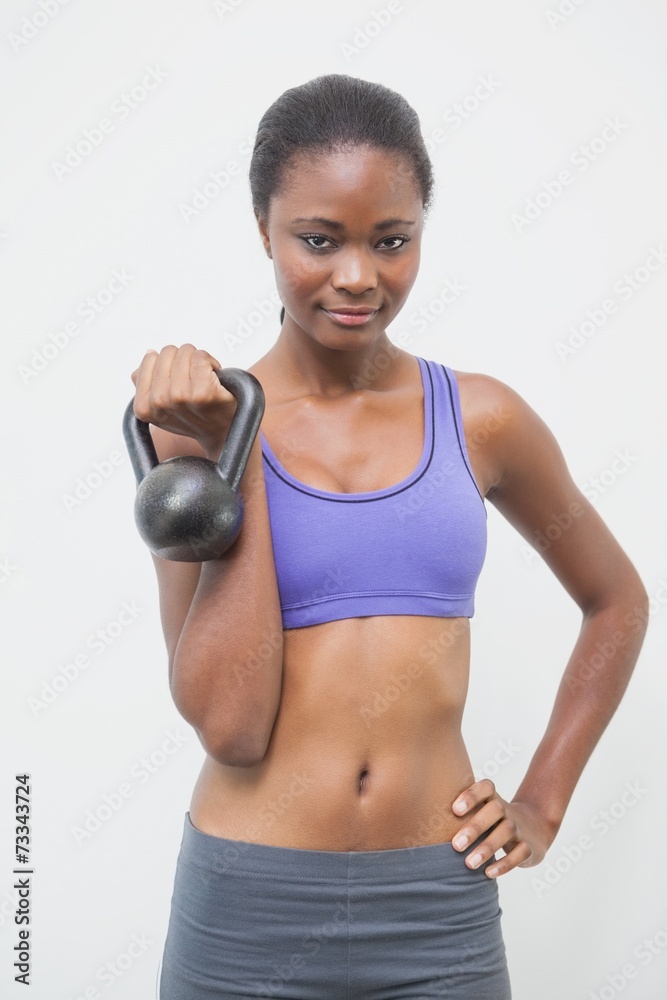Fit woman smiling at camera holding kettlebell Fit woman smiling at camera holding kettlebell